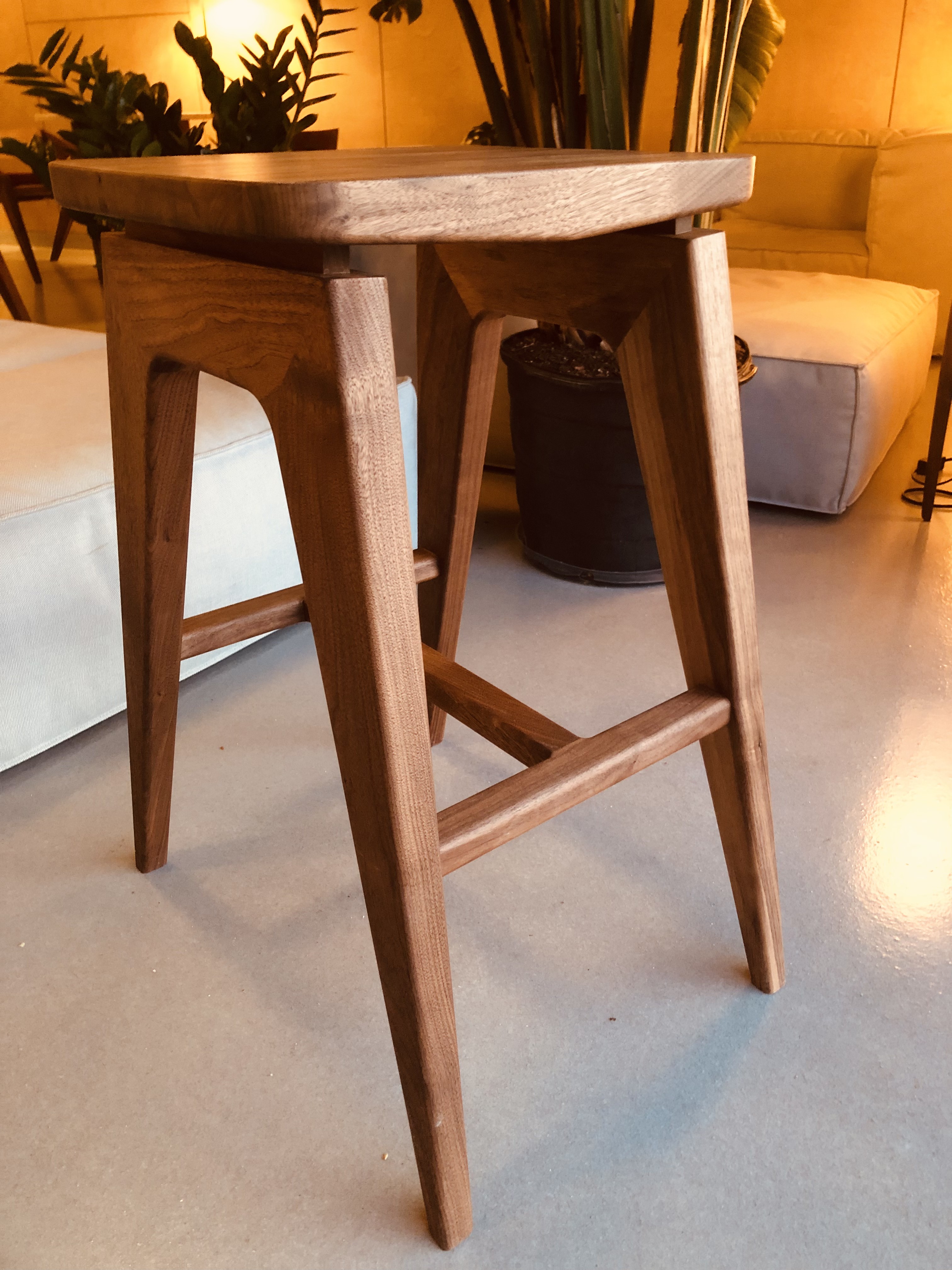 Handcrafted walnut side table with tapered legs in a warmly lit coastal showroom